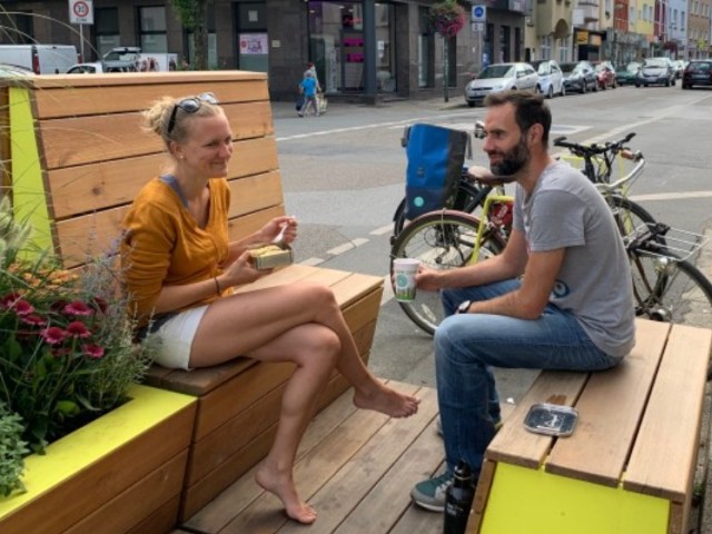 Personen sitzen in einem Parklet