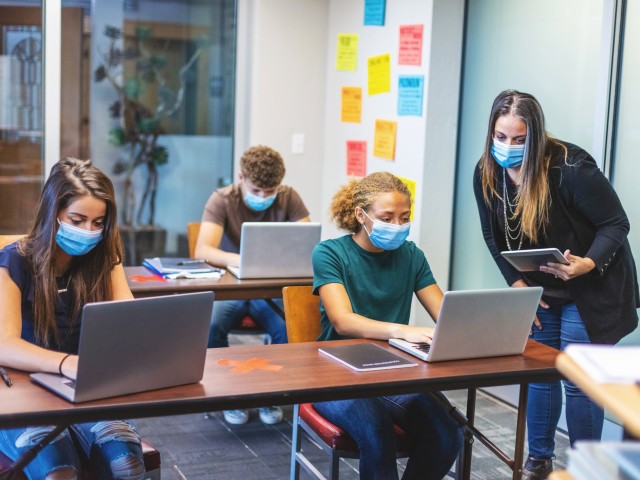 Foto: Klassenraum mit Kindern und Lehrer mit digitalen Mediengeräten