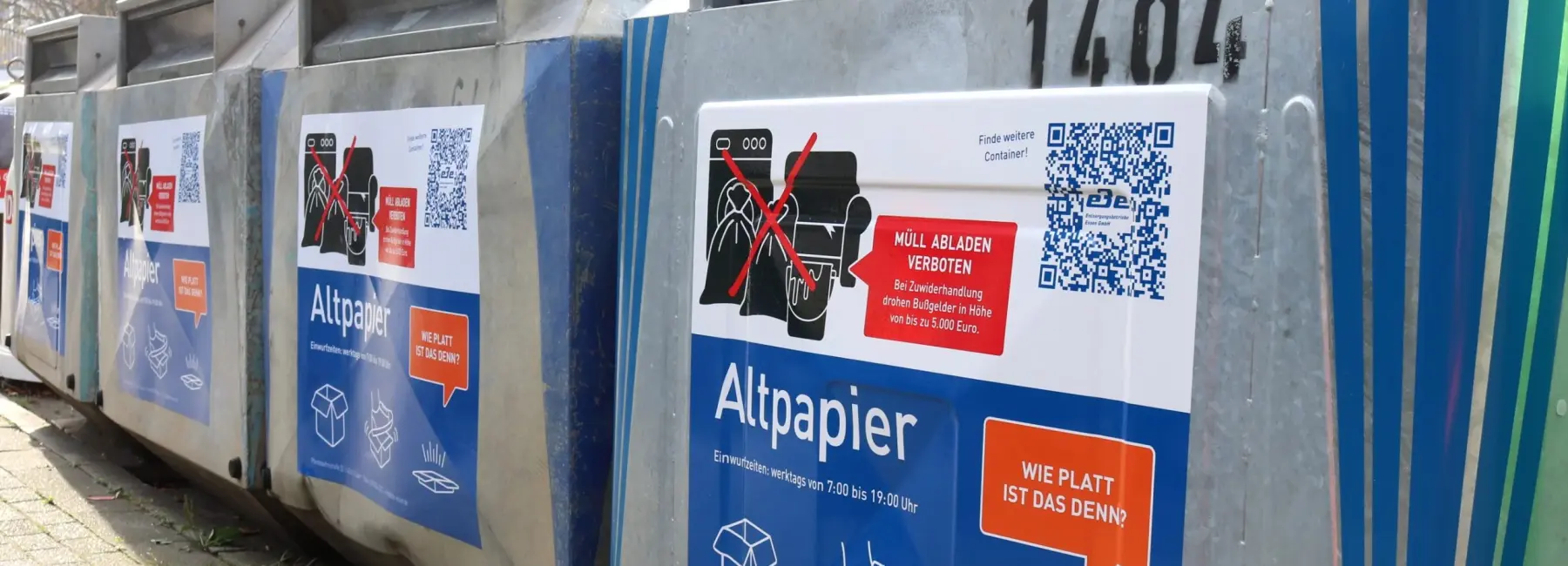 Foto: Altpapiercontainer mit Aufklebern die Tipps und QR Codes enthalten