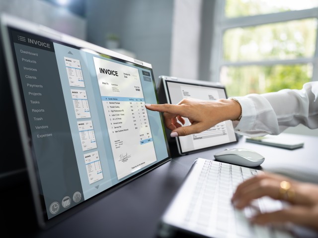 Hand zeigt auf digitalen Bildschirm, auf dem eine Rechnung zu sehen ist.