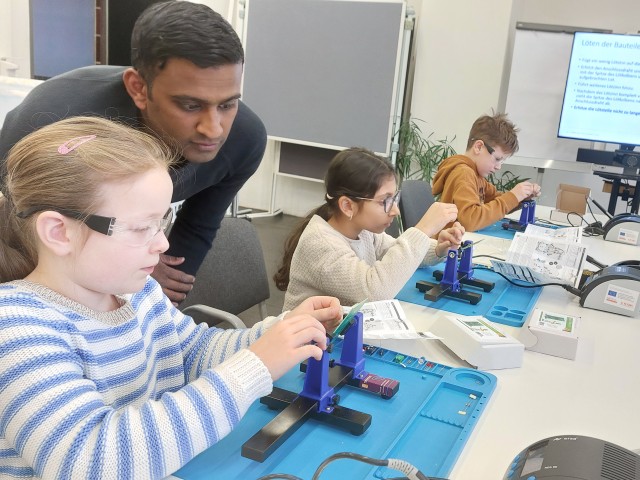 Foto: Kinder arbeiten unter Anleitung an elektronischen Bauteilen