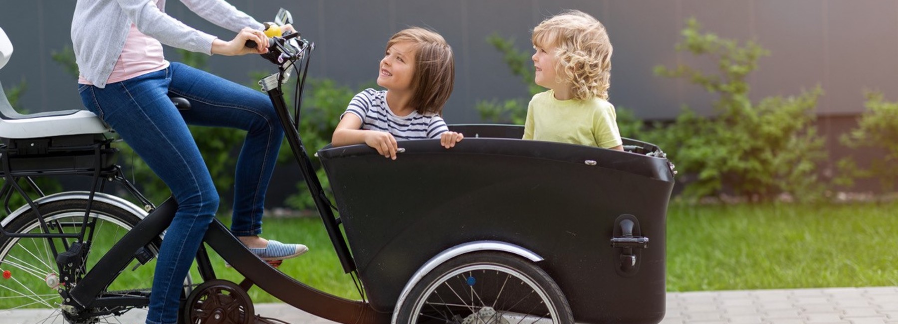 Foto: Kinder sitzen in einem Lastenrad, welches von einer Person gefahren wird