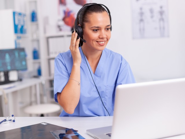 Foto: Medizinische Fachkraft mit Headset vor einem Notebook