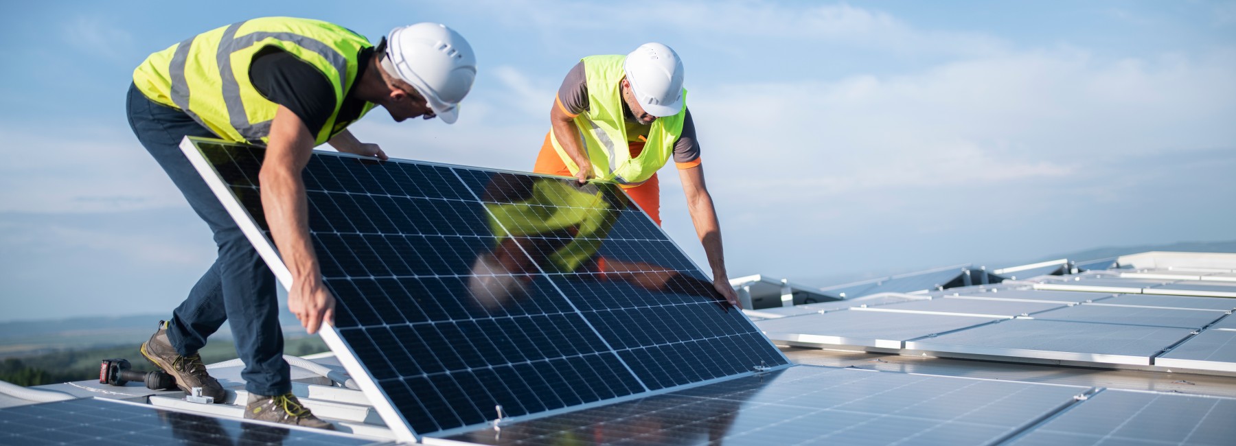 Foto: Bauarbeiter verlegen Photovoltaikanlagen am Gebäudedach