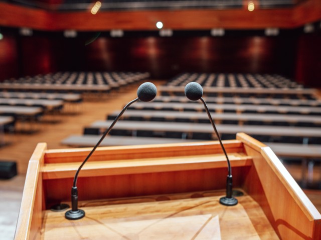 Foto: Ratssaal im Hintergrund eines Podiums mit Mikrofonen