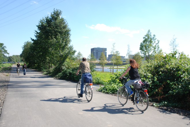 Radweg mit Fahrradfahrern und ThyssenKrupp-Hauptzentrale im Hintergrund