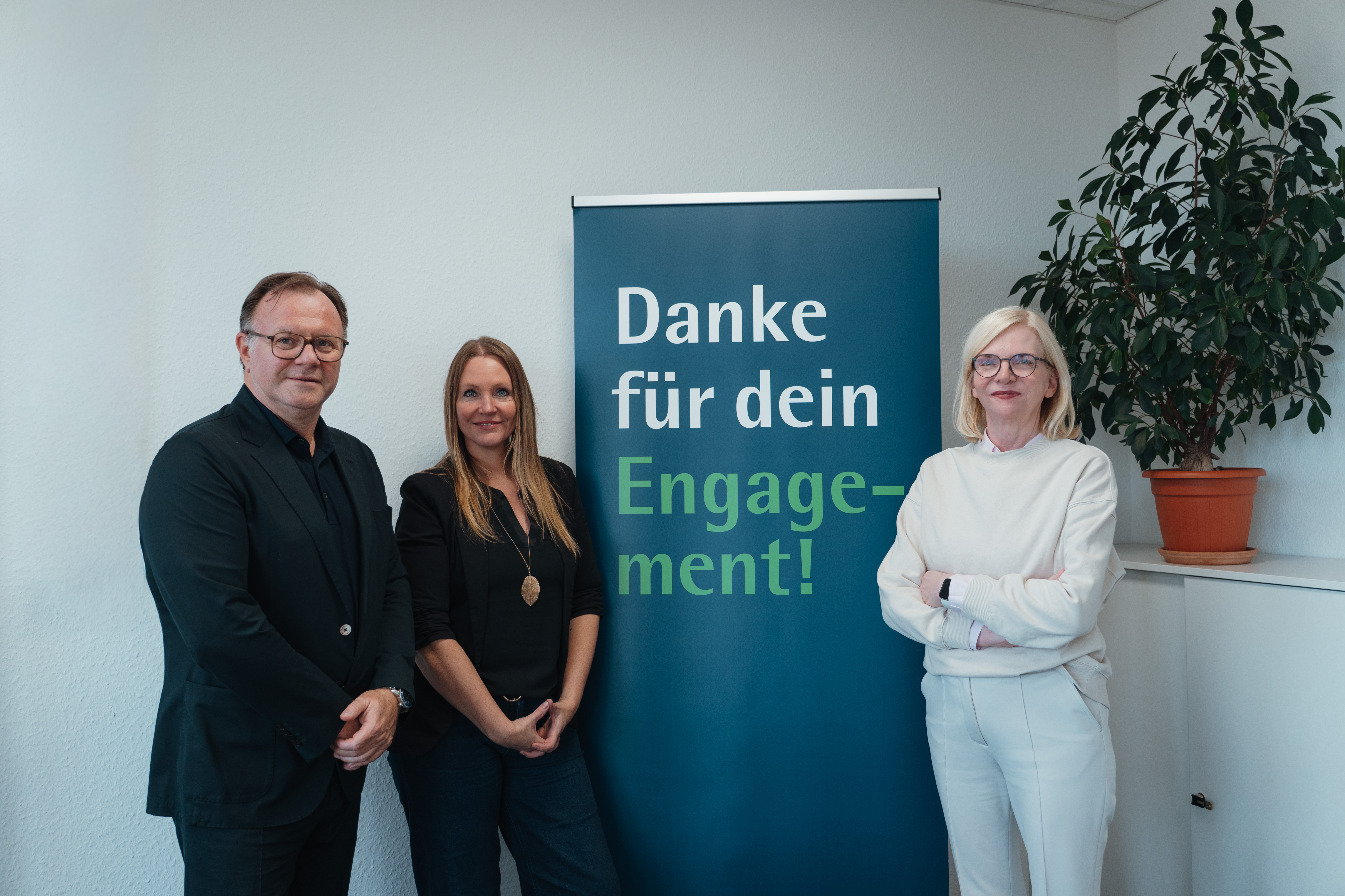 Foto: Jeanette von Lanken, Barbara Wolf und Stephan Bode vor einenm Roll-Up mit der Aufschrift "Danke für dein Engagement!"