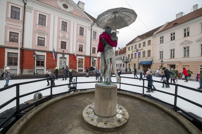 Das Bild zeigt das Rathaus der estnischen Stadt Tartu sowie im Vordergrund eine Skulptur mit zwei umschlungenen Personen.