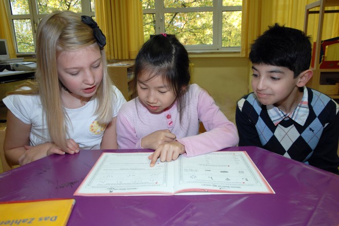 Foto: Drei Kinder lesen am Tisch
