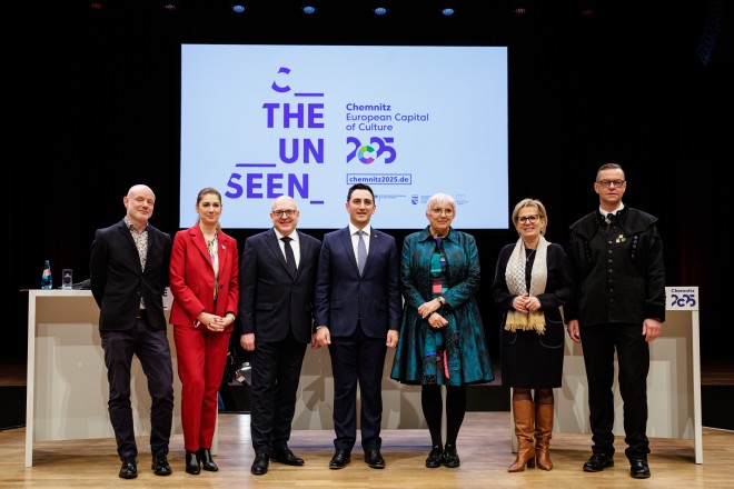 Das Bild zeigt den Sven Schulze (Bürgermeister von Chemnitz, EU-Kommissar Glenn Micallef und Claudia Roth (Kulturbeauftragte der Bundesregierung) auf einer Bühne anlässlich der Eröffnungsfreier der Kulturhauptstadt 2025 in Chemnitz. 