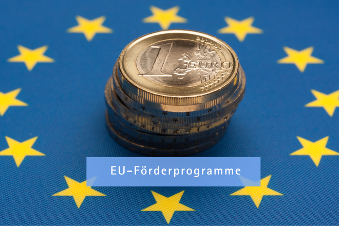 Aufeinandergestapelte Euro-Münzen liegen auf der EU-Flagge