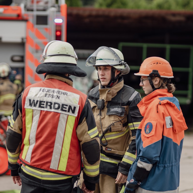 Foto: Zwei Kameraden der Freiwilligen Feuerwehr und eine Kameradin der Jugendfeuerwehr sprechen miteinander.