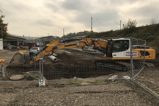 Foto: Blick auf die Baustelle, ein Bagger gräbt ein Loch