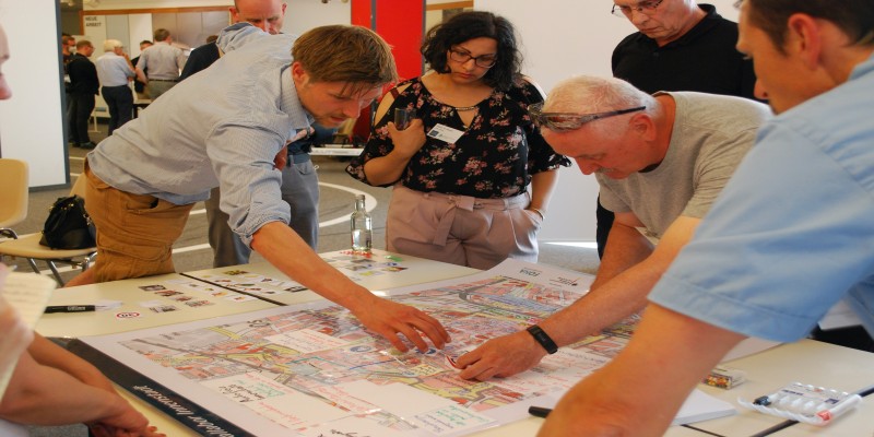 Menschen beugen sich an einem Tisch über einen Stadtplan