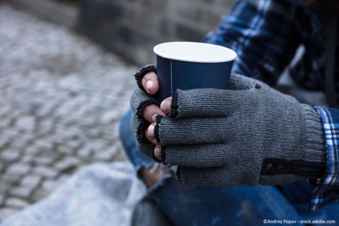 Foto: eine Person sitzt auf dem Boden und hält einen Kaffeebecher in beiden Händen