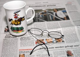 Foto: Brille und Tasse auf einer Zeitung
