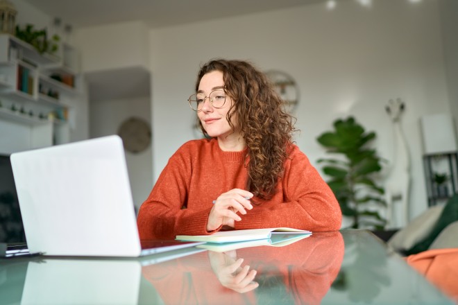 Frau sitzt vor dem Laptop zu Hause.