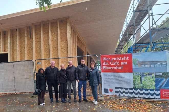 Foto: Projektverantwortliche stehen vor dem neuen Caf&eacute; im Essener Grugapark, das sich gerade im Bau befindet. Es handelt sich um ein Holzgeb&auml;ude.